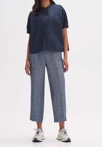 Camisa de botones de manga corta en color navy con un bolsillo en el pecho, combinada con pantalones de pierna ancha en azul claro que presentan una textura sutil y dos bolsillos frontales.