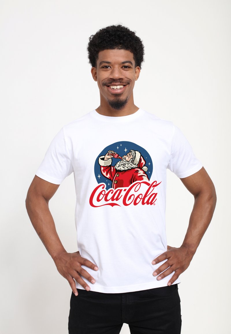 Hvid bomulds t-shirt med et retro Santa Claus grafisk design, livlige røde og blå farver, samt "Coca-Cola" tekst i kursiv stil.