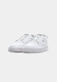 Hvite lær sneakers med rund tå, flate snøring, perforerte detaljer og subtil logo på siden og tungen. Teksturert gummisåle.