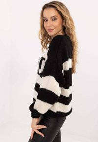 Schwarz-weiß gestreifter Strickpullover mit lockerem Schnitt, gerippten Bündchen und rundem Halsausschnitt. Strukturierter Wollmischgewebe.