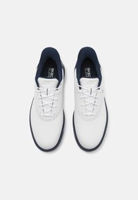 Des chaussures de sport blanches avec une tige en cuir lisse, des accents bleu marine et une partie avant perforée. Comprend des lacets blancs et un col rembourré.