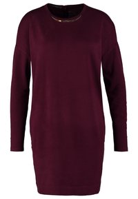 Robe bordeaux à manches longues avec un col rond et un accent métallique au niveau du col. Tissu doux, coupe droite, design longueur genoux.