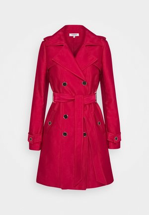Trench-coat rouge croisé avec larges revers, boutons noirs, ceinture à la taille et poignets boutonnés, présenté sur un fond uni.