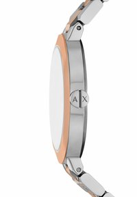 Silverfärgad klocka i rostfritt stål med rund klocka, rosaguldiga detaljer och minimalistisk design. Utmärkt med en knapp med "AX"-logotyp.