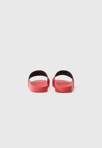 Røde gummisandaler med en glat overflade, åben bagpå og i siderne, flad sål og minimalistisk design. Enkel konstruktion uden udsmykninger.