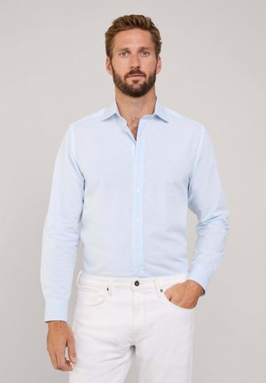 Camisa de botones azul claro con mangas largas, hecha de una tela texturizada. Presenta un cuello estándar y un cierre frontal de botones.