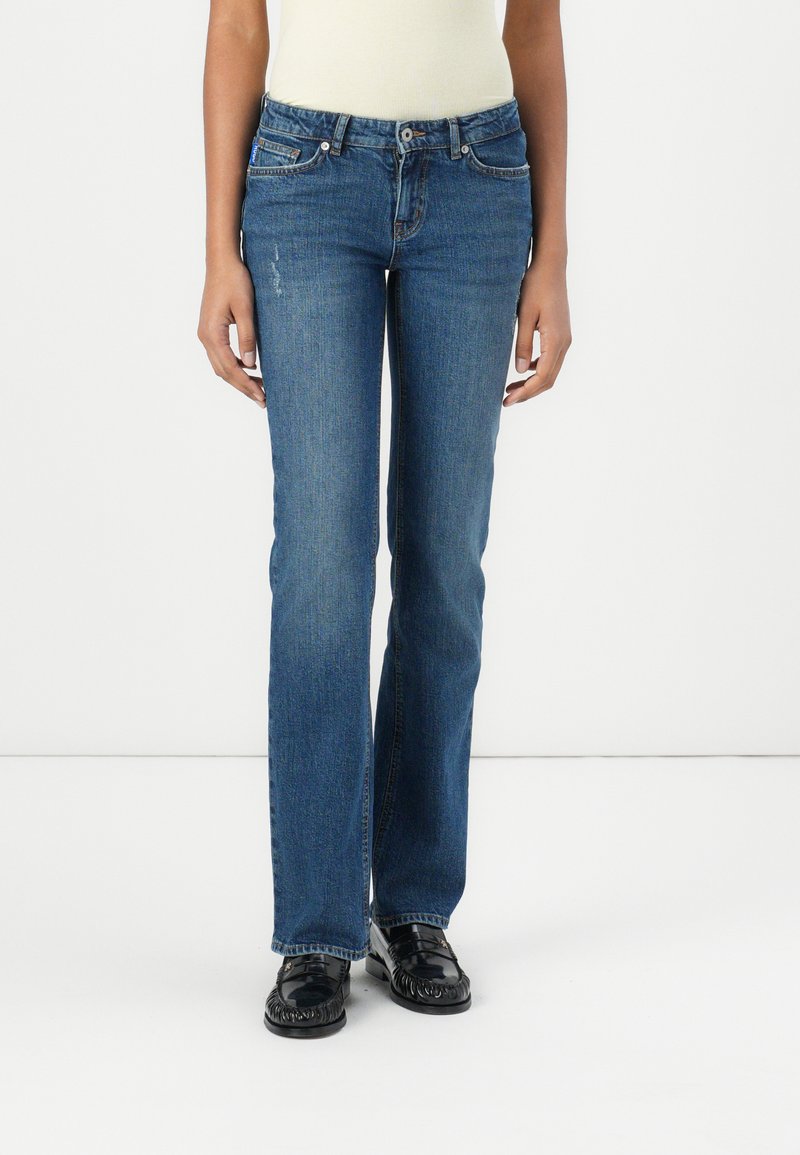 Blå denim jeans med rette ben, fem lommer, knappelukking og subtil falming ved lårene. Teksturert stofffinish.