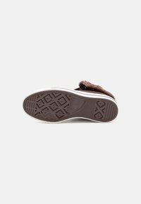 Brauner Außensohle mit Rauten- und Linienprofilen; weiße Zwischensohle; weicher, fellartiger Oberstoff; lässiges Slip-On-Design.