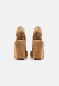 Sandales à plateforme beige avec un talon en corde tressée, un dessus perforé et une sangle réglable à la cheville. Texture lisse, design de talon carré.
