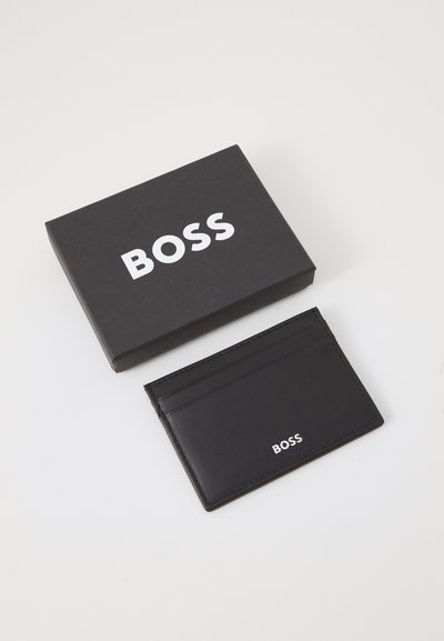Porte-cartes en cuir noir avec plusieurs fentes, arborant le logo blanc "BOSS". Comprend une boîte noire avec des lettres blanches. Texture lisse.