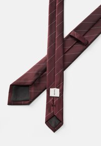 Βουργουνδίσης μεταξωτός γραβάτας με λευκές διαγώνιες ρίγες, με υφή και ετικέτα στο στενό άκρο. Κλασικός σχεδιασμός τριγωνικού άκρου.