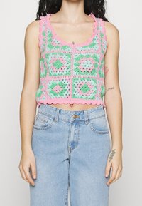 Crochet crop top in pastel green, pink, and blue with scalloped edges; features a geometric pattern, fitted design, and openwork texture.