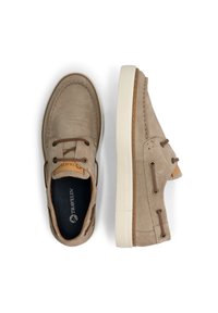 Zapatos náuticos de ante beige con cordones marrones, un costado perforado y una suela de goma blanca. El interior presenta una plantilla negra con un logo.