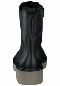 Botas de tobillo de cuero negro con una superficie texturizada, un forro corto de piel sintética en la parte superior y una suela de goma beige contrastante.
