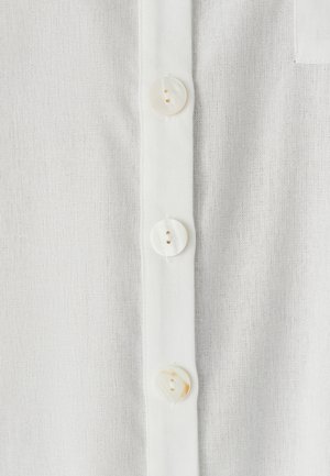 Baltas lino audinys su mygtukų sąvarža ir apvaliais perlų spindesio mygtukais. Audinys yra lengvas ir šiek tiek tekstūruotas.