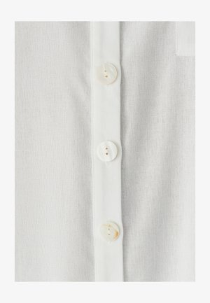 Biały len z plisą na guziki ozdobioną okrągłymi guzikami z masy perłowej. Materiał jest lekki i lekko fakturowany.