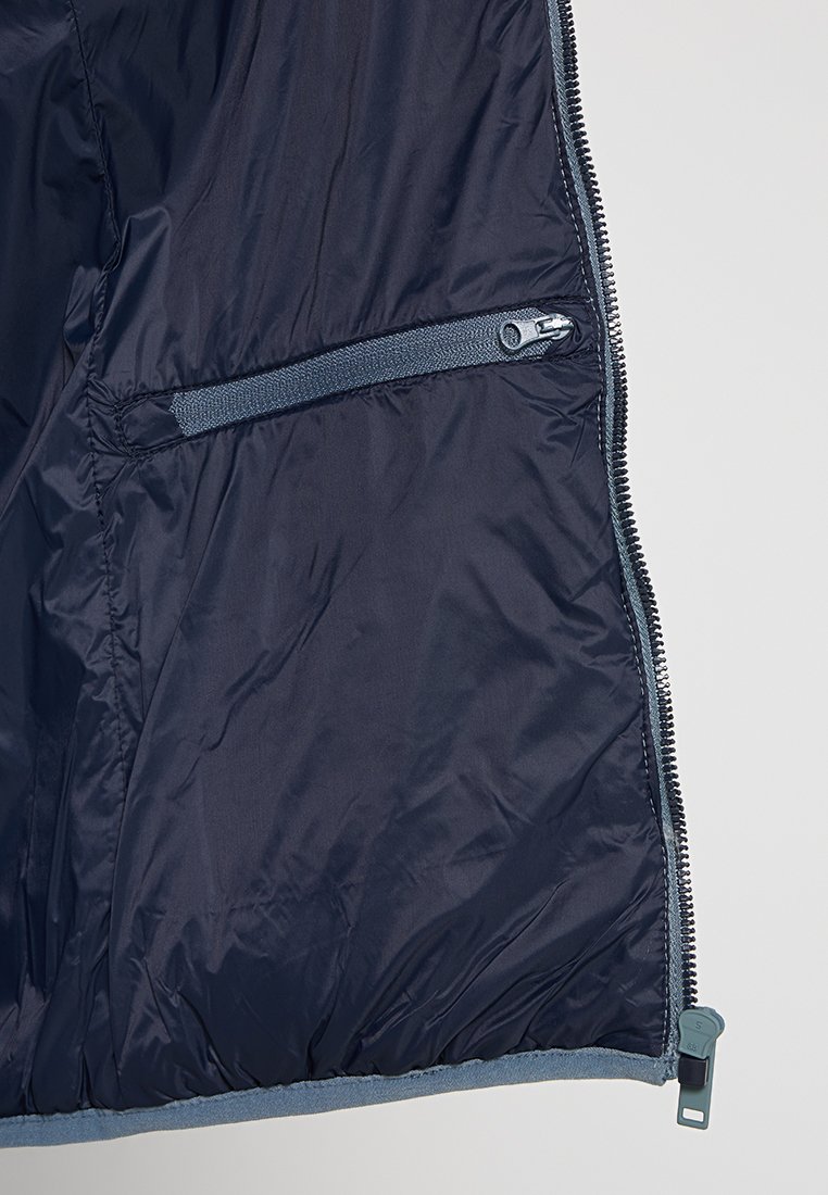 Innenseite einer marineblauen Daunenjacke mit einer Reißverschlusstasche auf der linken Seite, die eine glatte, leichte Textur und einen kontrastierenden hellgrauen Reißverschluss aufweist.