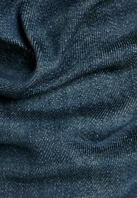 Materiał dżinsowy w głębokim odcieniu niebieskiego z delikatnie fakturowaną powierzchnią. Tkany wzór ukazuje drobne białe kropki, tworząc klasyczny motyw. Miękki i elastyczny.