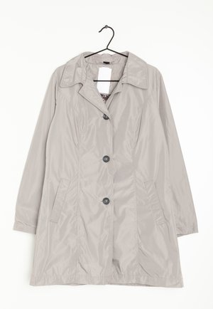 Trench-coat gris clair à manches longues, trois boutons noirs, deux poches avant et un col, suspendu à un cintre noir.