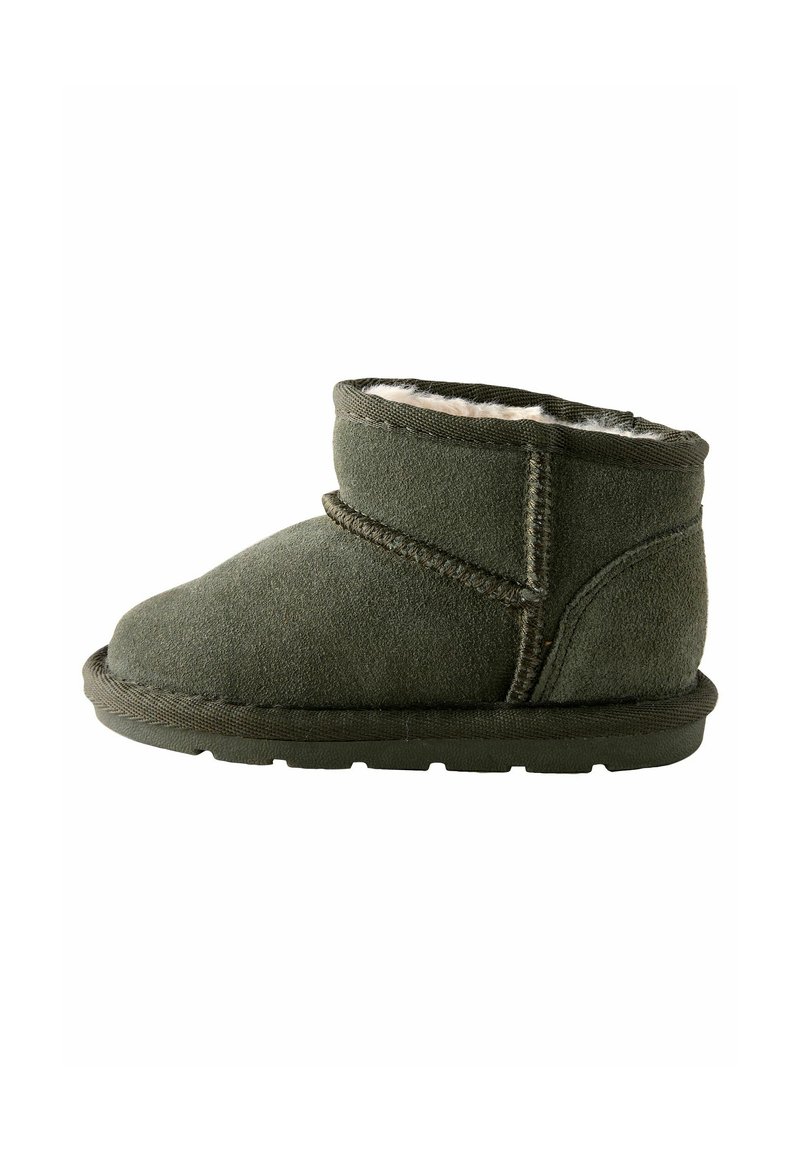 Olivgrüne Wildleder-Stiefelette mit einem weichen Futter aus Fell, niedrigem Profil, runder Zehenpartie und kontrastierenden Nähten. Flache Gummisohle.