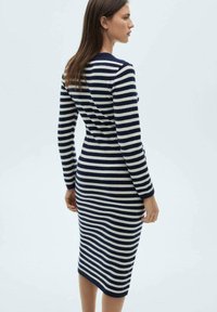 Abito in maglia con strisce orizzontali navy e crema, maniche lunghe, silhouette aderente e lunghezza al ginocchio con una superficie liscia.
