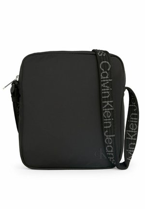Borsa a tracolla in nylon nero con forma quadrata, chiusura con zip e una tracolla decorata con il logo "Calvin Klein Jeans".