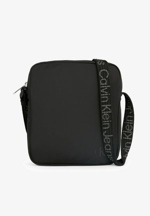 Borsa a tracolla in nylon nero con forma quadrata, chiusura con zip e una tracolla decorata con il logo "Calvin Klein Jeans".