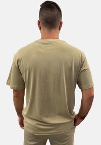 Beige Baumwoll-T-Shirt mit kurzen Ärmeln, Rundhalsausschnitt und lockerer Passform. Glatte Textur und einfaches Design, keine sichtbaren Muster oder Logos.