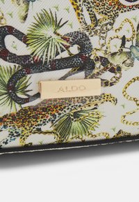 Aldo wallet with a textured white canvas featuring vibrant animal prints, including leopards and snakes, accented by a gold logo plaque.