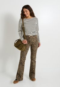 Top de rayas de manga larga, ajustado en la cintura, combinado con pantalones acampanados de estampado de leopardo. Bolso verde oliva con correa, zapatos marrones con estampado.