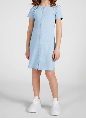 Vestido azul claro acanalado con mangas cortas, con cierre de botones al frente y una abertura en el dobladillo. Combinado con zapatillas blancas.