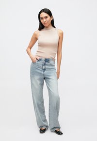Beige ribbed sleeveless top paired with light blue wide-leg jeans. Black pointed-toe flats complement the outfit. Simple, clean design.