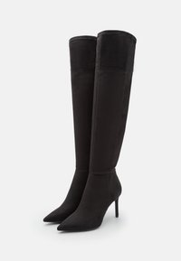 Svarta över-knä stövlar i mocka, med spetsig tå och stilettklack. Slät yta med minimala sömnadsdetaljer.