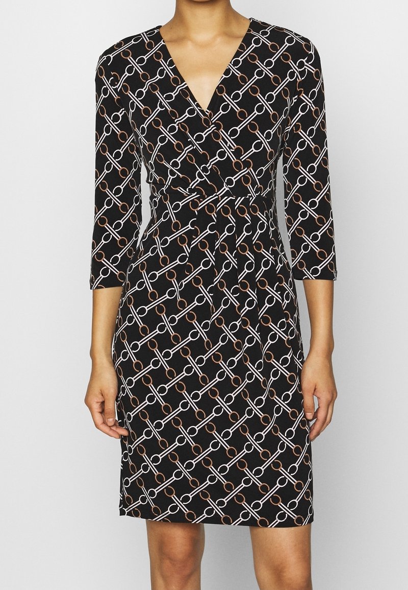 Robe portefeuille noire avec un motif géométrique de chaînes en blanc et cuivre, manches trois-quarts et taille ajustée. Texture du tissu lisse.