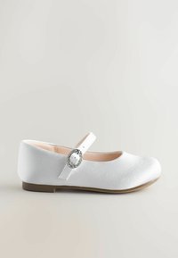 Scarpa piatta bianca realizzata in tessuto liscio, con punta rotonda e una fascia con una fibbia decorativa rotonda. Suola piatta e design minimale.