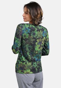 Long-sleeve shirt featuring a dark background adorned with green and blue floral patterns, made from soft, textured fabric.