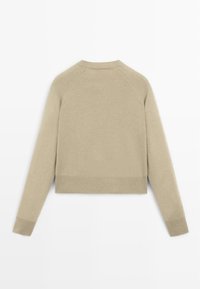 Maglione beige a collo rotondo, con maniche lunghe e polsini e orlo a coste. Realizzato in un morbido tessuto testurizzato con una finitura liscia.