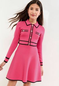 Rosa gestricktes Kleid mit langen Ärmeln, schwarzen Akzenten an Kragen und Ärmeln, durchgehende Knopfleiste mit dekorativen Knöpfen, schwingendes Rockdesign.