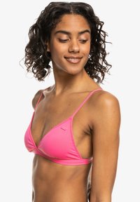 Roze driehoekige bikinitop met dunne verstelbare bandjes en een gladde stof. Minimalistisch ontwerp zonder extra patronen of versieringen.