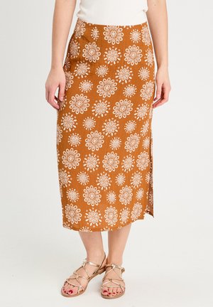 Bruine bloemen midi-rok met witte bloempatronen en een zijopening. Draagt met goudkleurige sandaaltjes met banden. Soepele textuur, aansluitend ontwerp.