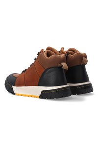Bruine en zwarte high-top schoenen van textuurleer en mesh, met contrasterende zool en gewatteerde kraag. Heeft een vetersluiting en een trekhaak aan de achterkant.