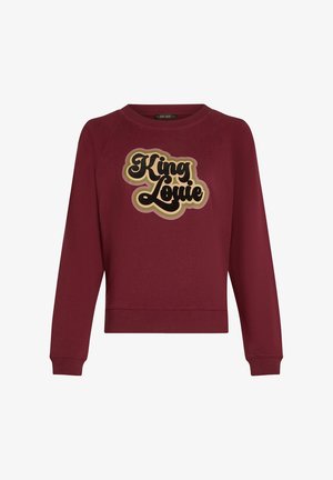 Bordowy sweter z okrągłym dekoltem i długimi rękawami raglanowymi. Na przodzie znajduje się duża grafika "King Louie" w czerni i złocie.