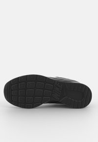 Svart Nike-sneaker sula med rutmönstrad mönster och Nike-logotyp präglad nära fotvalvet, visad mot en simpel vit bakgrund.