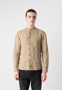 Camisa de lino beige con cuello tipo banda, cierre frontal de botones y mangas largas. Tejido texturizado con un corte relajado.