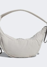 Beige vadderad axelväska med en kurvad design och mjuk textur. Har ett dragkedjestängning och en tunn, rundad rem.