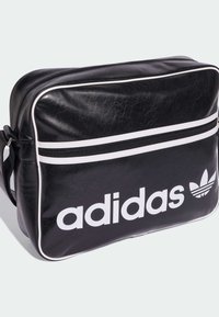 Melnā sintētiskā soma ar baltām akcentiem, taisnstūra forma, viens rāvējslēdzēja nodalījums, liels "adidas" logo un trīs svītru logo detaļa.