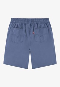 Pantalones cortos de cintura elástica azul con dos bolsillos traseros y una pequeña etiqueta roja en la costura del bolsillo derecho, exhibidos de forma plana sobre un fondo blanco.