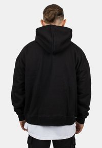 Black hooded sweatshirt, relaxed fit, cotton blend fabric, ribbed cuffs and hem, solid color with no visible patterns, back view.