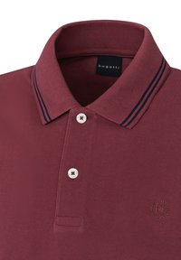 Polo di colore bordeaux con una finitura testurizzata, dotato di una patta con tre bottoni, logo ricamato e strisce in contrasto di colore navy sul colletto.