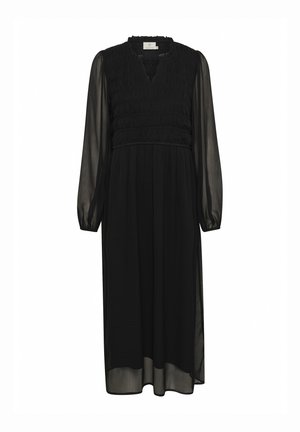 Vestido negro de manga larga con un cuerpo fruncido y escote en V. La tela ligera y fluida crea una silueta suave, con mangas translúcidas.